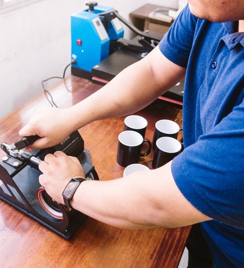 A male working on the printing machine for cups